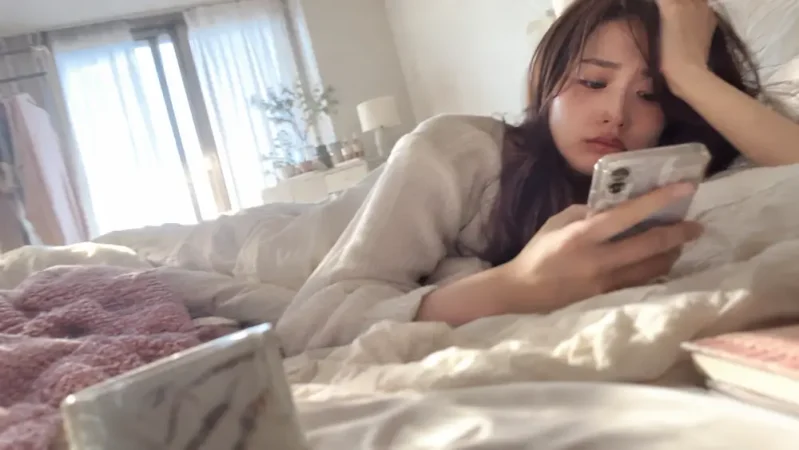 ベッドでスマホを見る女性